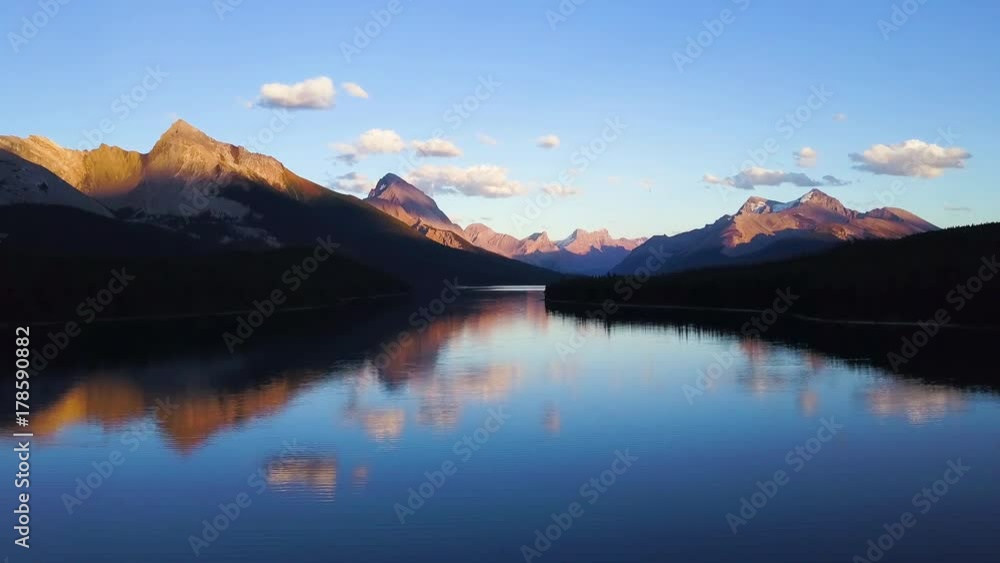 Aerial shot above lake with reflections of Rocky Mountains in Canada while sunset Aerial shot above lake with reflections of Rocky Mountains in Canada while sunset