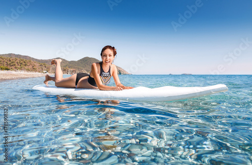 Young beautiful woman relaxing lying in the blue sea on a sup board near Chirali beach  Turkey