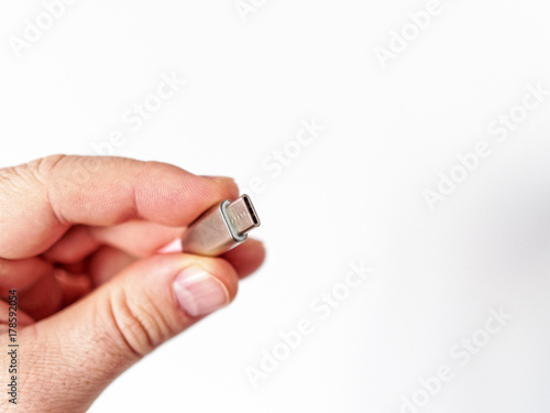 Man's hand holds cable usb type c on a green background