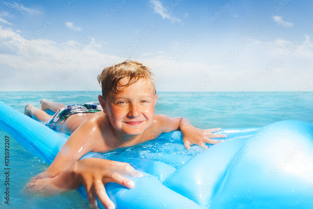 Boy on the blue matrass swim in sea