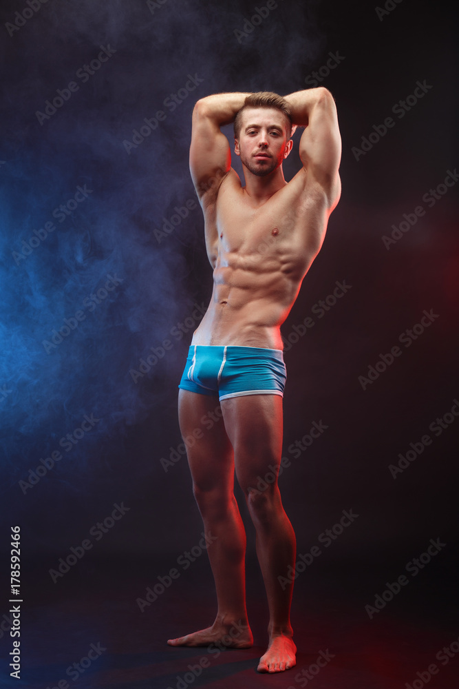 Bodybuilding, sports, weightlifting, fitness concept. Young muscular fit man with perfect body posing, vertical image