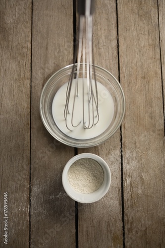 Directly above shot of milk with wire whisk and flour in