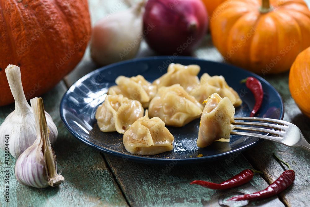Vegan pumpkin manti, traditional homemade steamed dumplings served with pumpkins, garlic and onions on shabby rustic table Vegan pumpkin manti, traditional homemade steamed dumplings served with pumpkins, garlic and onions on shabby rustic table