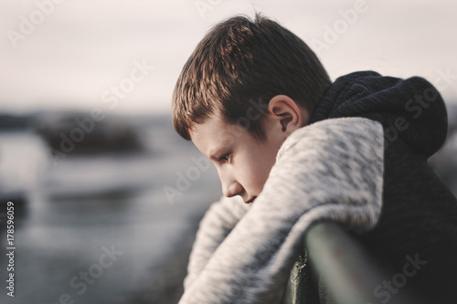 Sad little boy leaning over railing
