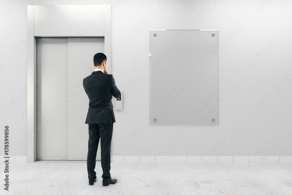 Fototapeta premium Businessman with poster and elevator