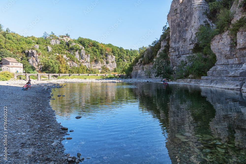People playing in the river Ardeche near the bridge near the picturesque village of Labeaume