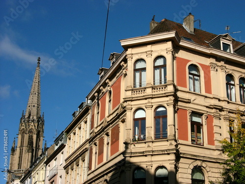 Prachtvolle Altbauten und Kirchturm der Herz Jesu Kirche im Herbst vor blauem Himmel im Sonnenschein in Köln am Rhein in Nordrhein-Westfalen