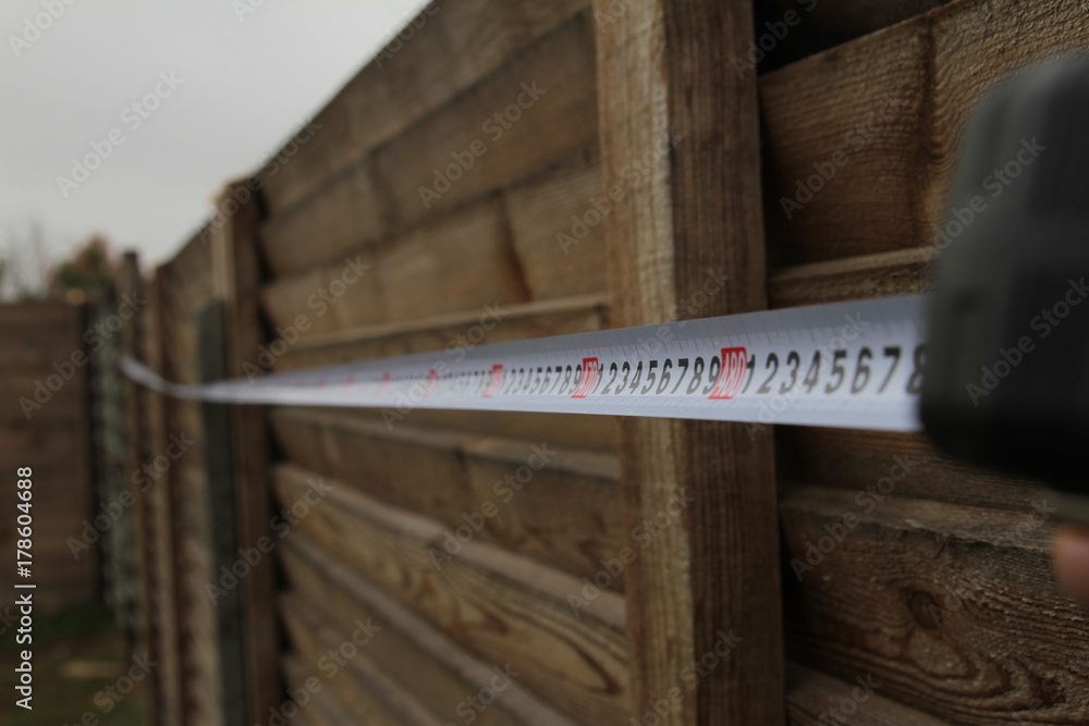 Measurement of a fence with a construction tape measure in the suburban area