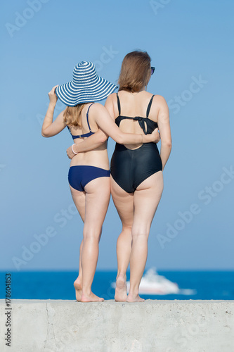 Two girls in swimsuits against the sky, rear view