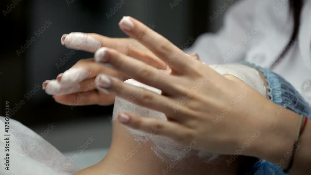 The cosmetologist does face massage to the client in excess of the mask The cosmetologist does face massage to the client in excess of the mask