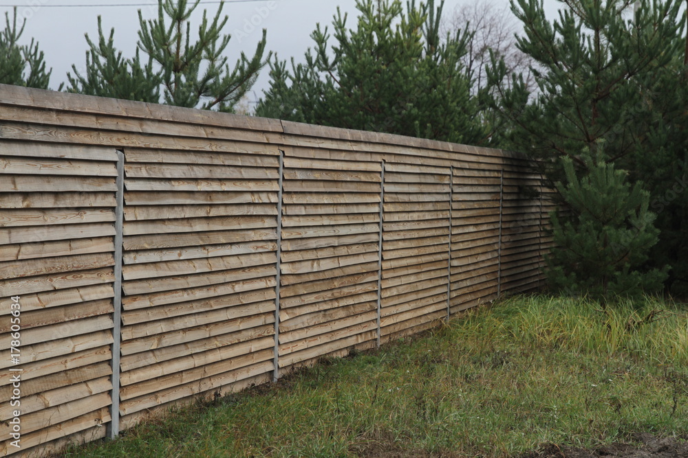 Fence in the suburban area with a forest near the trees. Fencing of private territory. Refugee shelter in Europe Fence in the suburban area with a forest near the trees. Fencing of private territory. Refugee shelter in Europe