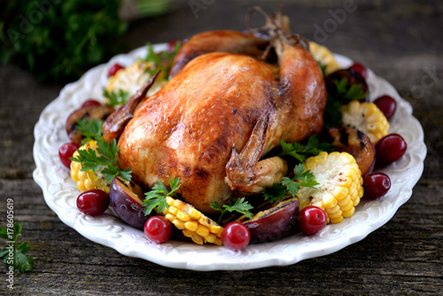 Grilled chicken on Thanksgiving day with corn, plum, dogwood and parsley. photo