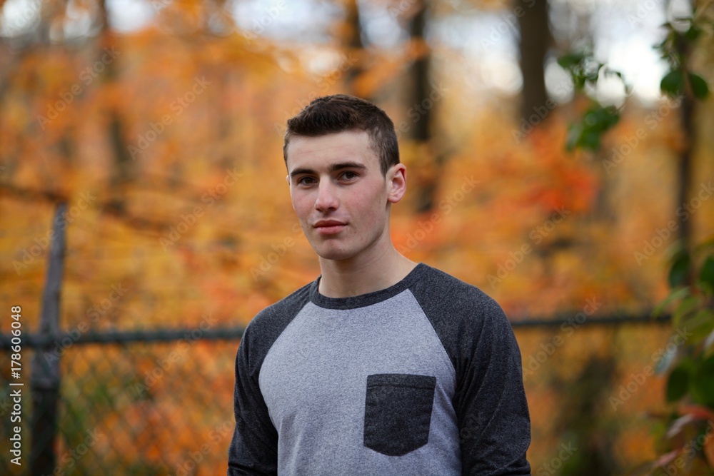 Φωτογραφία Portrait head shot of a teenage boy outside in front of an orange tree in autumn