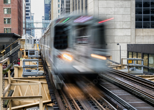 Moving Train on elevated tracks within buildings at the Loop, Glass and Steel bridge between buildings - Chicago City Center - Long Exposure - Chicago, Illinois, USA