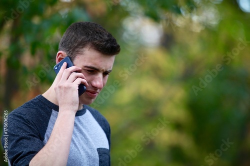 Foto Teenage boy answering a phone call outside