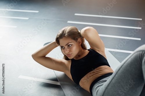Posh young woman doing abs crunches to prepare her body for the summer. Fitness concept.