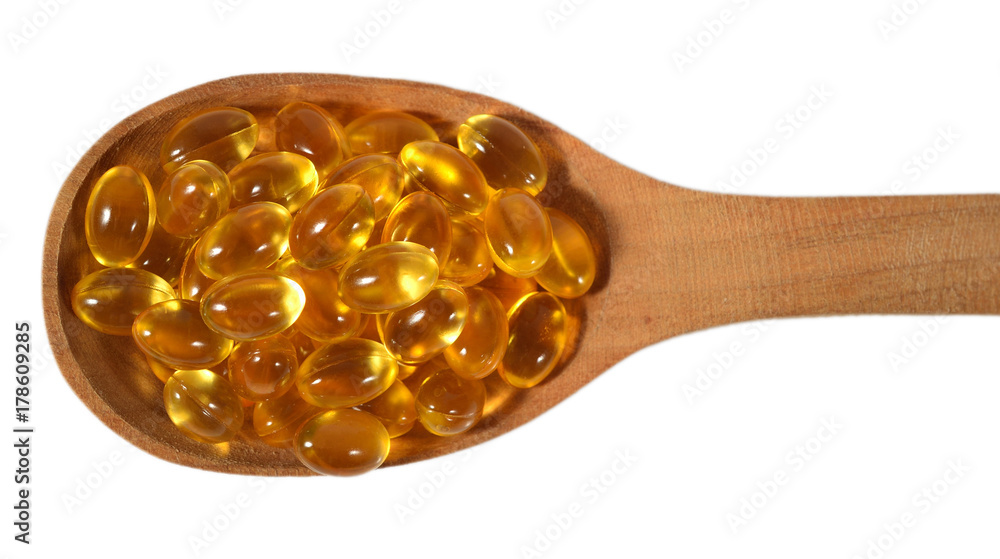 Omega-3 fish fat oil capsules in wooden spoon on a white Omega-3 fish fat oil capsules in wooden spoon on a white