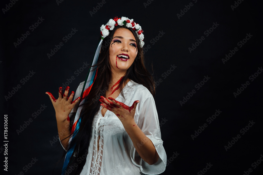 Portrait of a bloody beautiful Asian girl on Halloween. White dress-robe, ethnic wreath of flowers. Portrait of a bloody beautiful Asian girl on Halloween. White dress-robe, ethnic wreath of flowers.