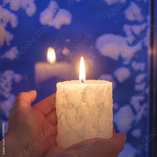 Christmas candle against the background of a snow-covered window