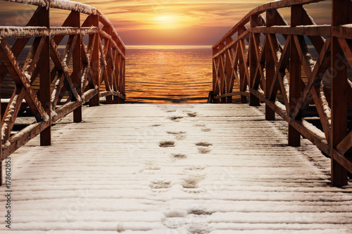 wooden walkways, pier, covered with snow, lead to the river at sunset