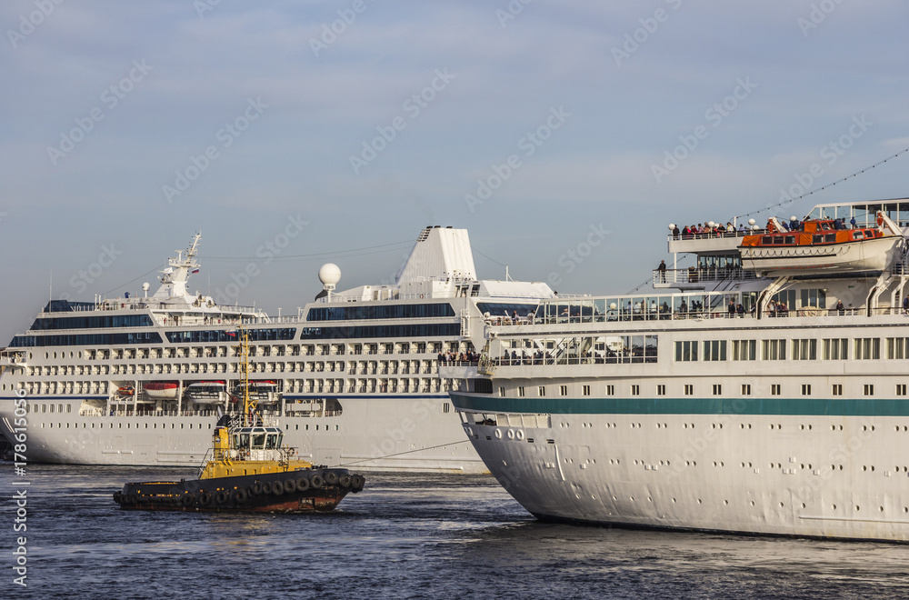 A huge cruise ships being manouvered and reversed towards high sea by pilots and tugboats A huge cruise ships being manouvered and reversed towards high sea by pilots and tugboats