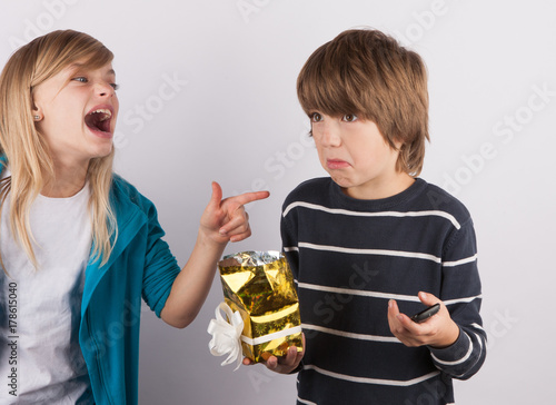 Boy got a simple mobile phone in a gift box, his sister laughing on him