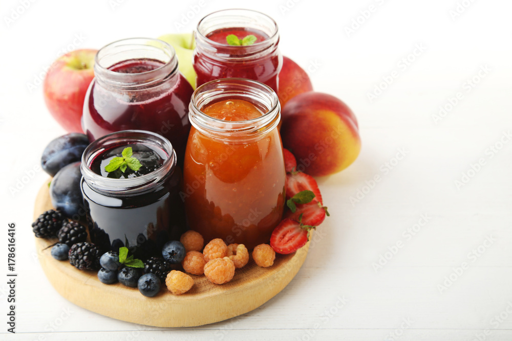 Glass jars with different kinds of jam and berries on wooden table Glass jars with different kinds of jam and berries on wooden table