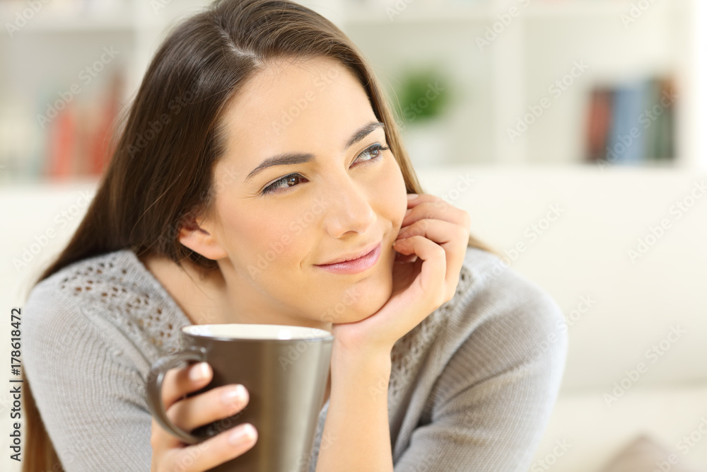 Pensive woman holding a coffee cup looking at side Pensive woman holding a coffee cup looking at side