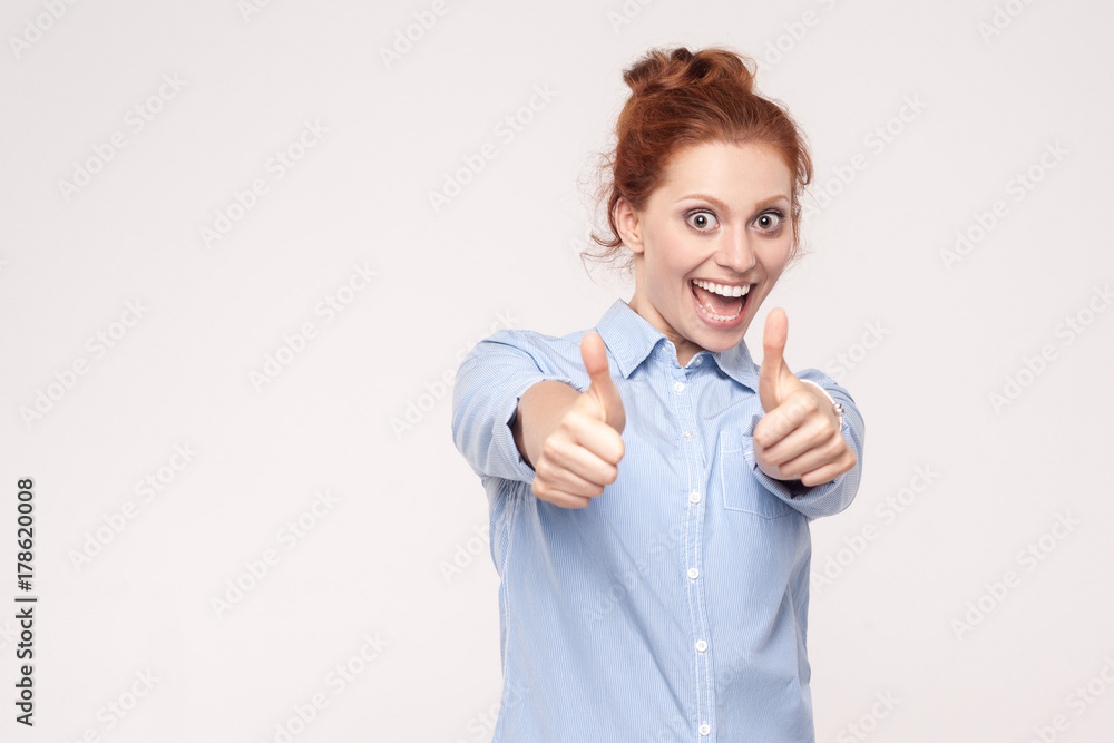 Happy cheerful redhead woman showing thumb up and toothy smile. Happy cheerful redhead woman showing thumb up and toothy smile.