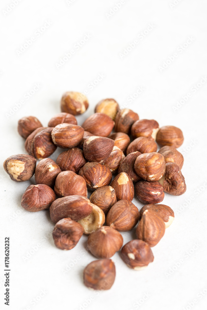 Pile of raw hazelnuts isolated above white marble stone Pile of raw hazelnuts isolated above white marble stone