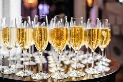  Elegant glasses with champagne standing in a row on serving table during party or celebration