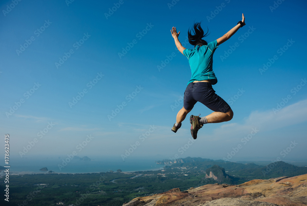 joyful woman hiker jumping on rocky mountain top joyful woman hiker jumping on rocky mountain top