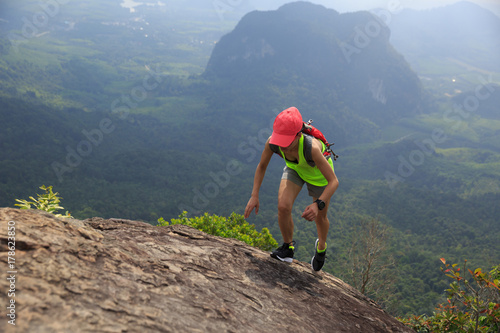 Young fitness woman trail runner running up to mountain top
