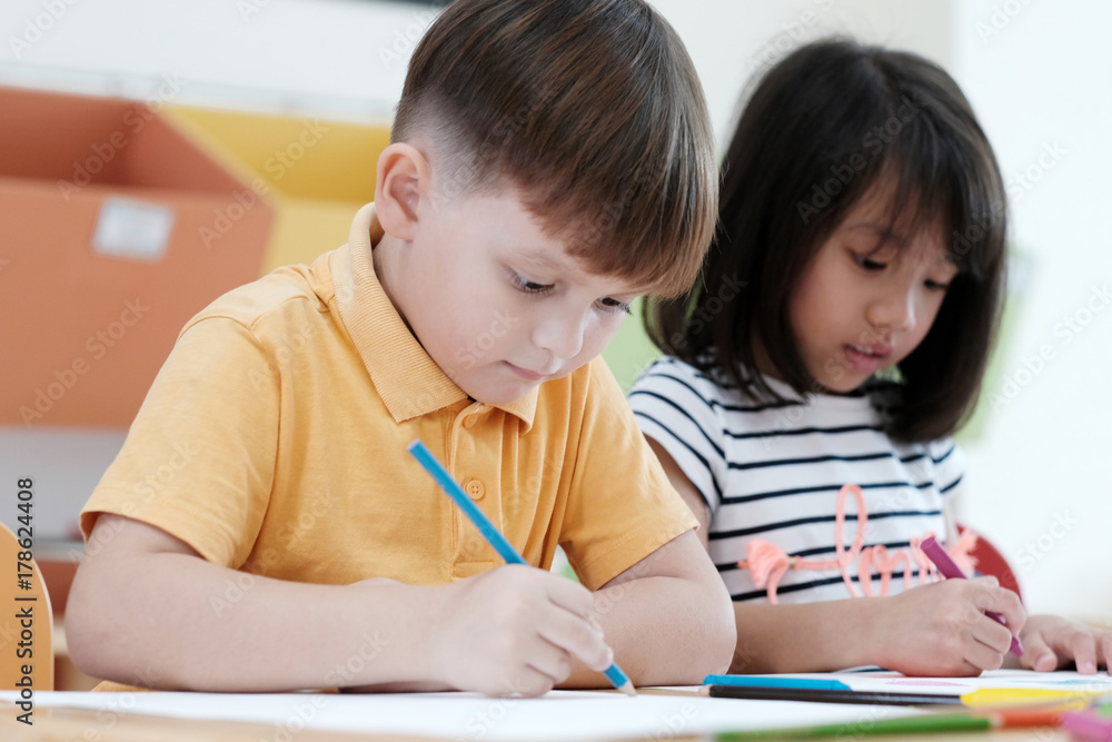 Boy and girl drawing color pencils in kindergarten classroom, preschool and kid education concept Boy and girl drawing color pencils in kindergarten classroom, preschool and kid education concept