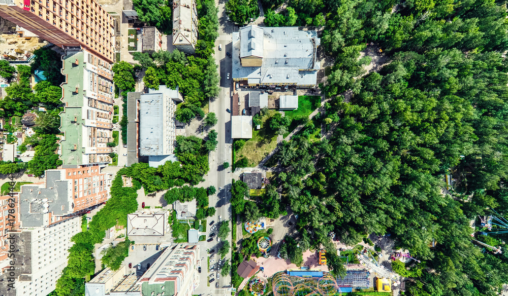 Fototapeta premium Aerial city view with crossroads and roads, houses, buildings, parks and parking lots, bridges. Helicopter drone shot. Wide Panoramic image.