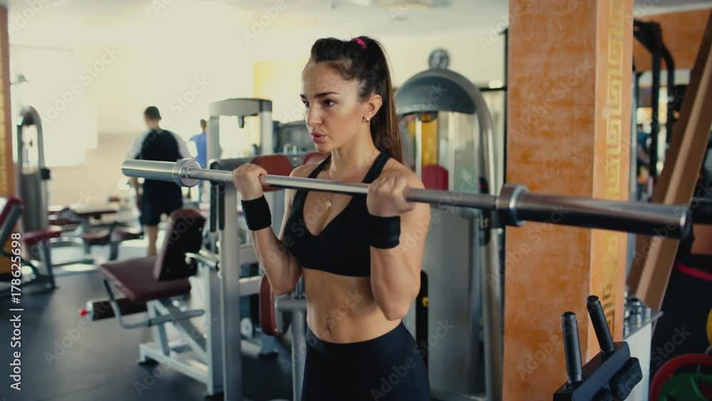 Young sporty woman brunette with long hair lifting barbell bar in gym. 4 k Young sporty woman brunette with long hair lifting barbell bar in gym. 4 k
