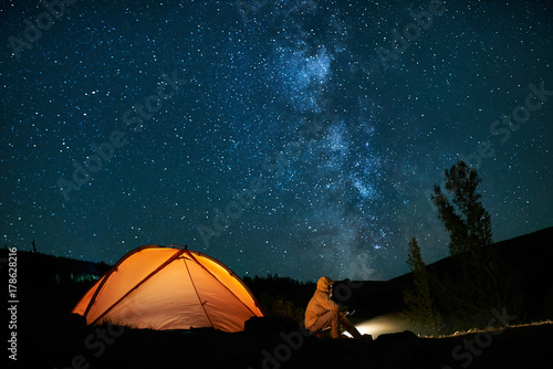 Man tourist near his camp tent at night. Fototapeta