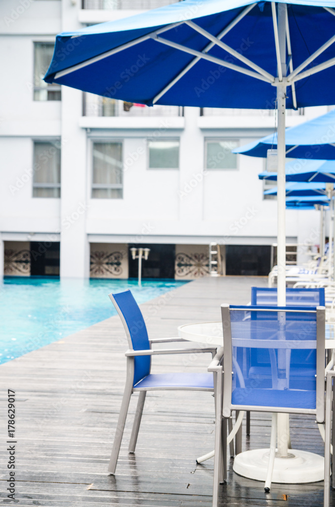 Swimming pool with umbrellas and chairs for relaxing in the hotel. heavy light and bokeh. Tech little artificial light.