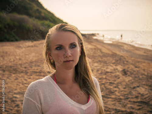 Beautiful woman on the beach on the background of green hill.