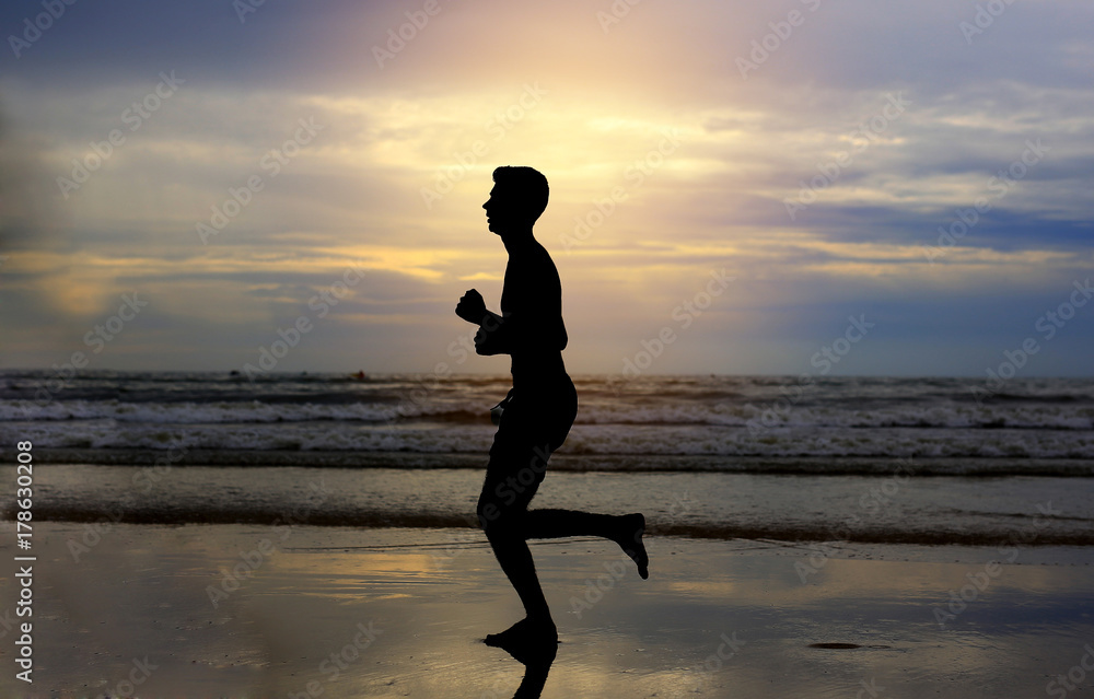 Man running on the beach at sunset.