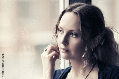 Sad young woman looking out the window