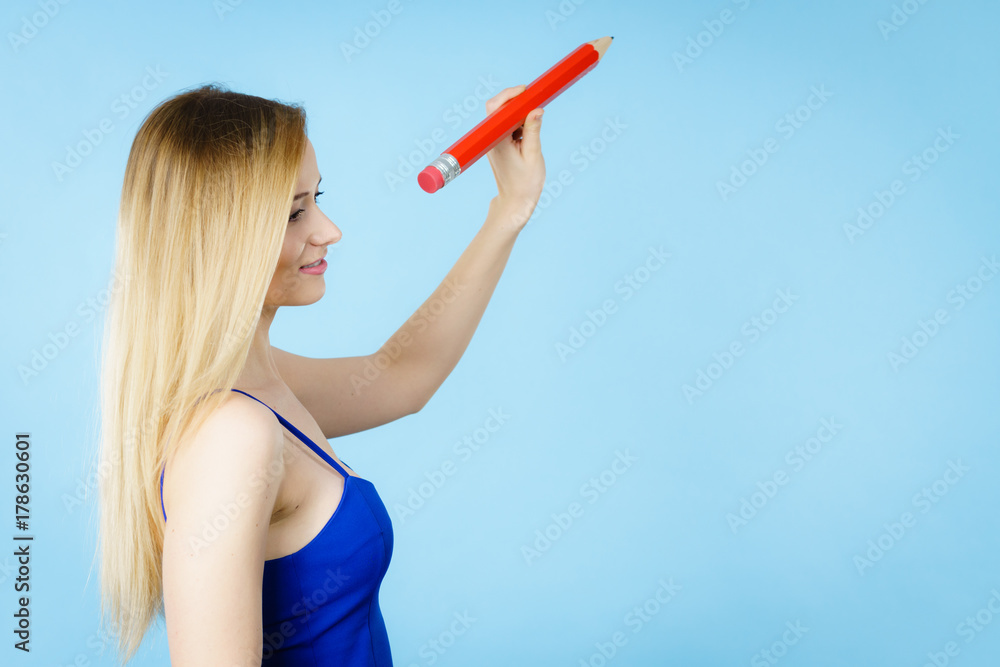 Blonde woman holds big pencil in hand drawing Blonde woman holds big pencil in hand drawing