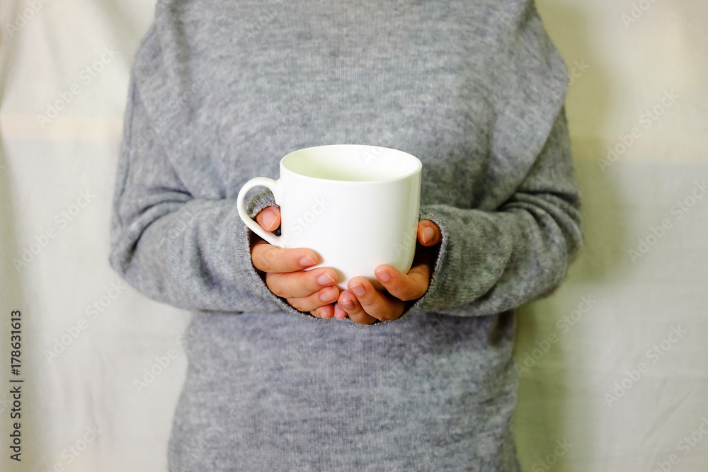 Hand holding warm drink with grey sweater Hand holding warm drink with grey sweater