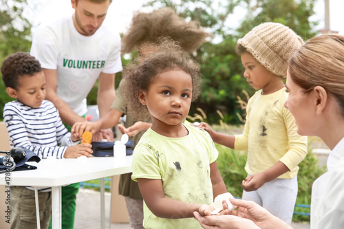 Photos Volunteers giving vitamin tablets to poor African children outdoors