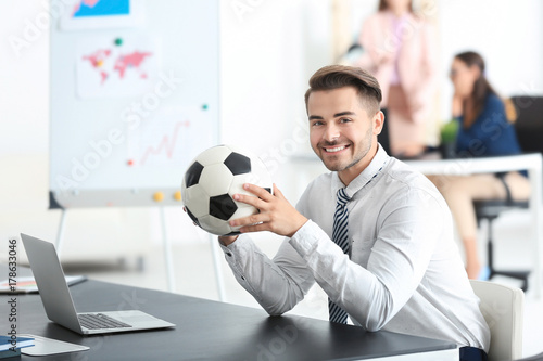 Fototapeta Naklejka Na Ścianę i Meble -  Young handsome man with soccer ball in office