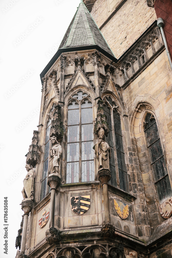 Part of the exterior of the beautiful old temple on the main square in Prague with black roof against gray sky background