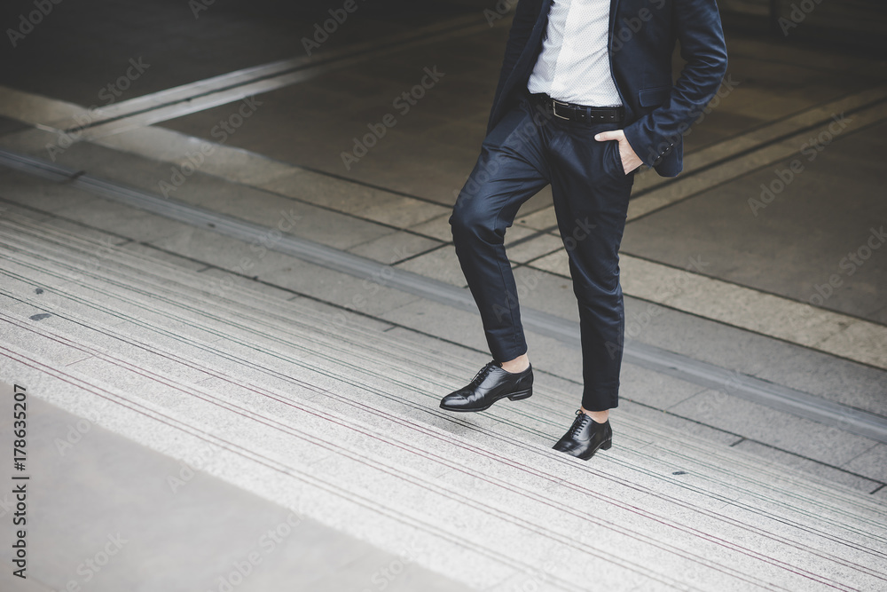Obraz premium Close up of young businessman walking upstairs outside office.