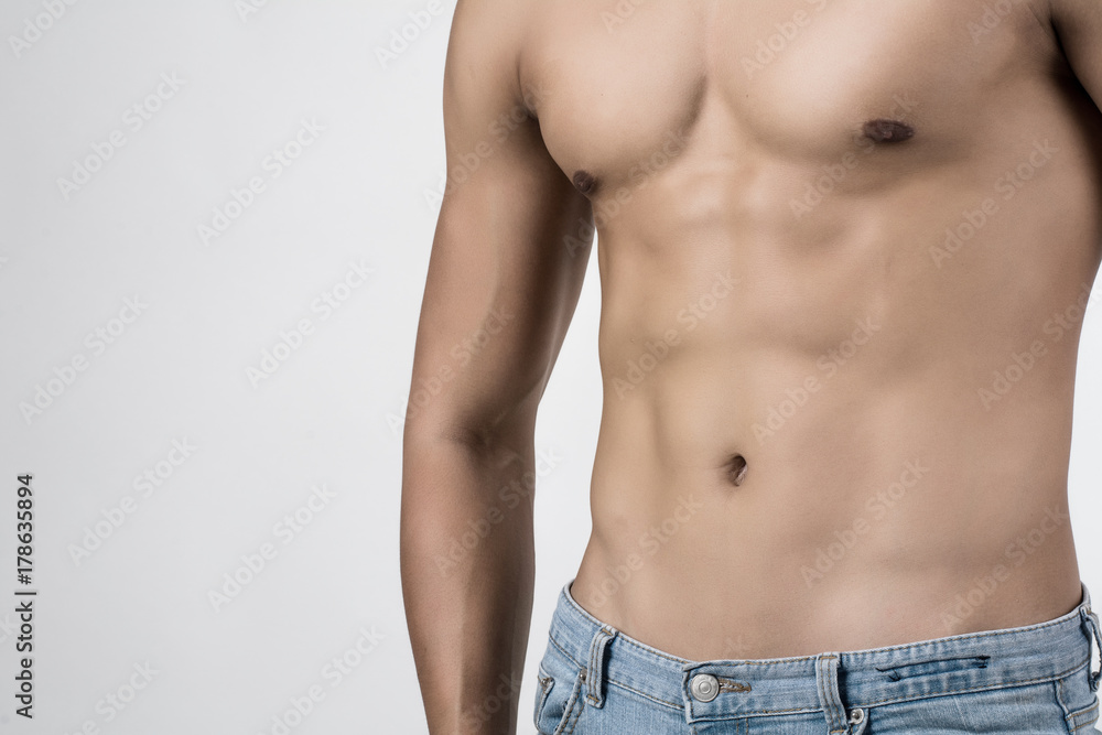 Young handsome fit man posing his muscles isolated on white background with copyspace.
