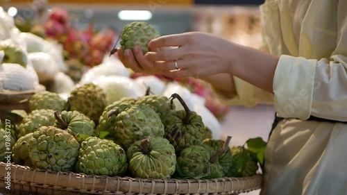 Womans hands choosing the custard apple or sugar apple in the supermarket photo