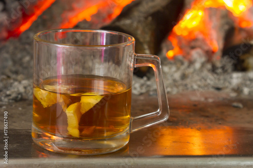 Tea with lemon on the background of a burning fireplace